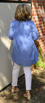 Bsck view a blue shirt and white pants 
