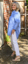 Side view a blue striped shirt and white pants .
