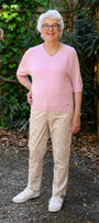 Woman in a pink shirt and beige pants front view.