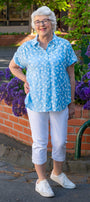 Woman in a blue shirt and white pants front view.