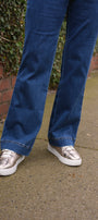 Person wearing blue jeans and silver sneakers .