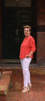 Woman in a orange sweater and white pants.