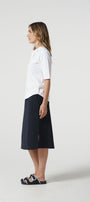 Woman wearing a white shirt and navy skirt on a white background