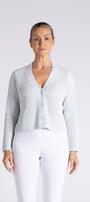 A woman modeling a light blue textured knit cardigan with a V-neck and button-front closure, paired with white pants, against a plain light gray studio background.