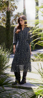 Woman in a patterned dress standing in a garden with greenery around