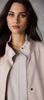 Woman wearing a light pink jacket against a gray background