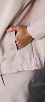 Person wearing a pink jacket with a hand in the pocket, blurred background
