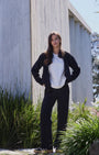 Woman standing in Black waist length jacket with pockets and matching wide leg pants .
