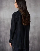 Woman wearing a black pinstripe shirt against a gray background