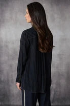 Woman wearing a black pinstripe shirt against a gray background