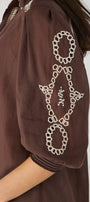Brown garment with white geometric pattern .