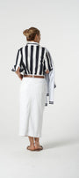 Person wearing a black and white striped shirt and white pants on a white background
