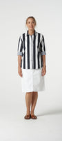 Person wearing a black and white striped shirt and white pants on a white background