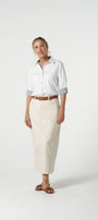Woman wearing a white shirt and cream skirt on a white background
