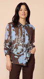 Woman wearing a brown floral blouse against a beige background
