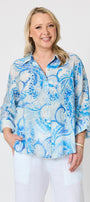 light blue and white paisley print button up blouse with white pants.