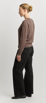 Woman wearing a brown sweater and black pants on a white background