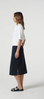 Woman wearing a white shirt and navy skirt on a white background