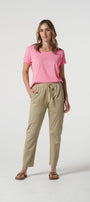 Woman wearing a pink t-shirt and beige pants on a white background