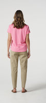 Person wearing a pink t-shirt and beige pants on a white background