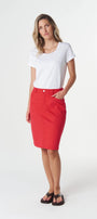 A woman modeling a bright red knee-length pencil skirt with a white short-sleeve t-shirt and black sandals, standing against a plain white studio background.