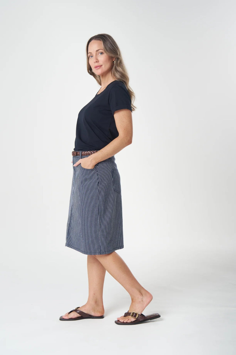 Woman wearing a black top and blue skirt on a white background