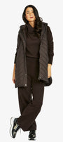 Woman wearing a dark brown outfit with a puffer vest on a white background