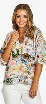 Front view  short sleeve button up shirt with a colorful tropical beach print, paired with white pants, against a plain light grey background.
