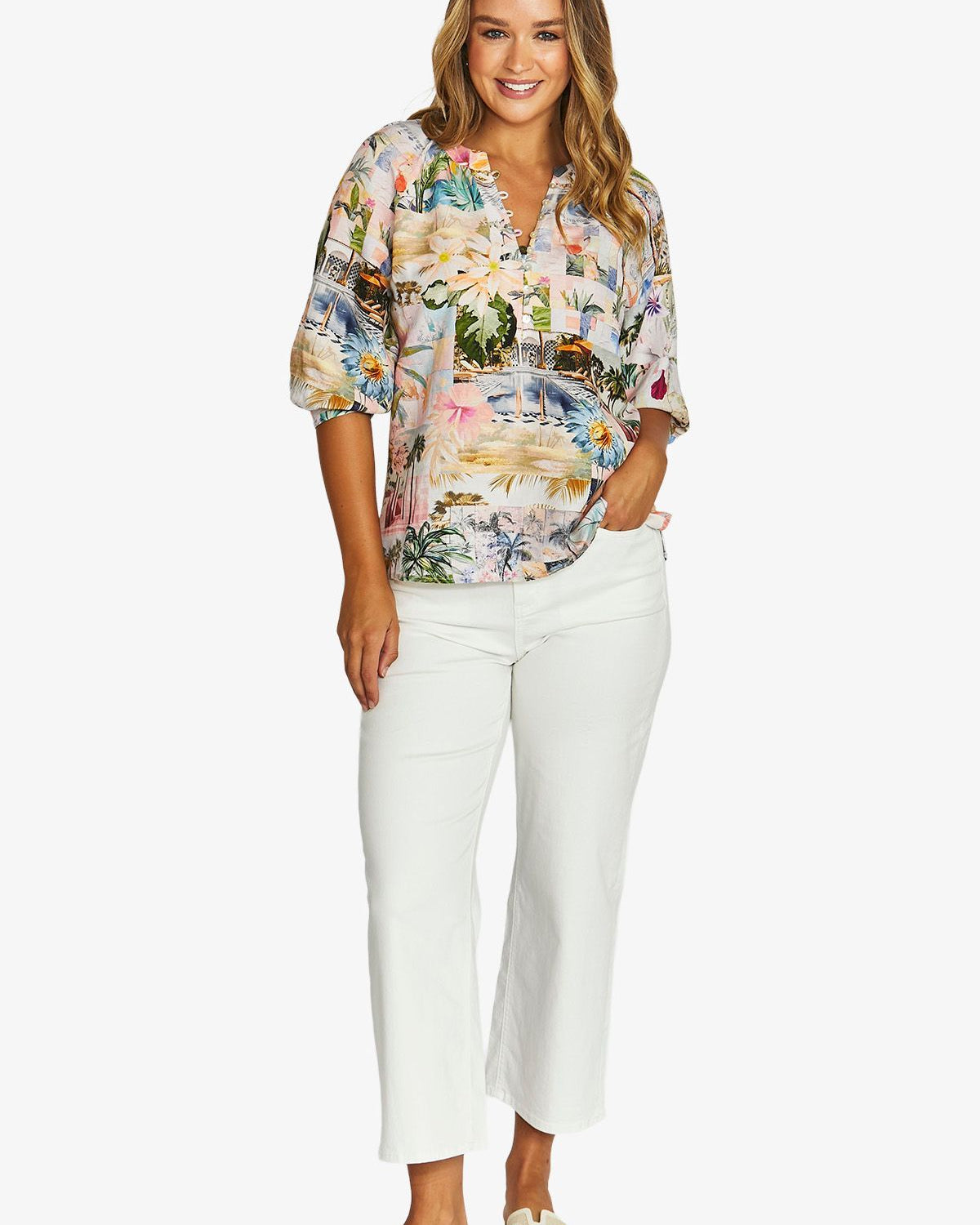 Front View  short sleeve button up blouse with a colourful tropical floral print, paired with white cropped pants and beige slide sandals.