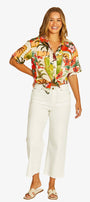 Front View short sleeve button up shirt with a colorful tropical floral print, paired with white cropped pants and beige slide sandals.