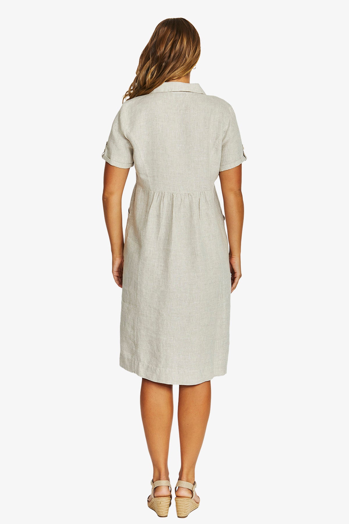 Back view  wearing a light beige short sleeve linen dress with a collar and gathered waist, paired with beige sandals.