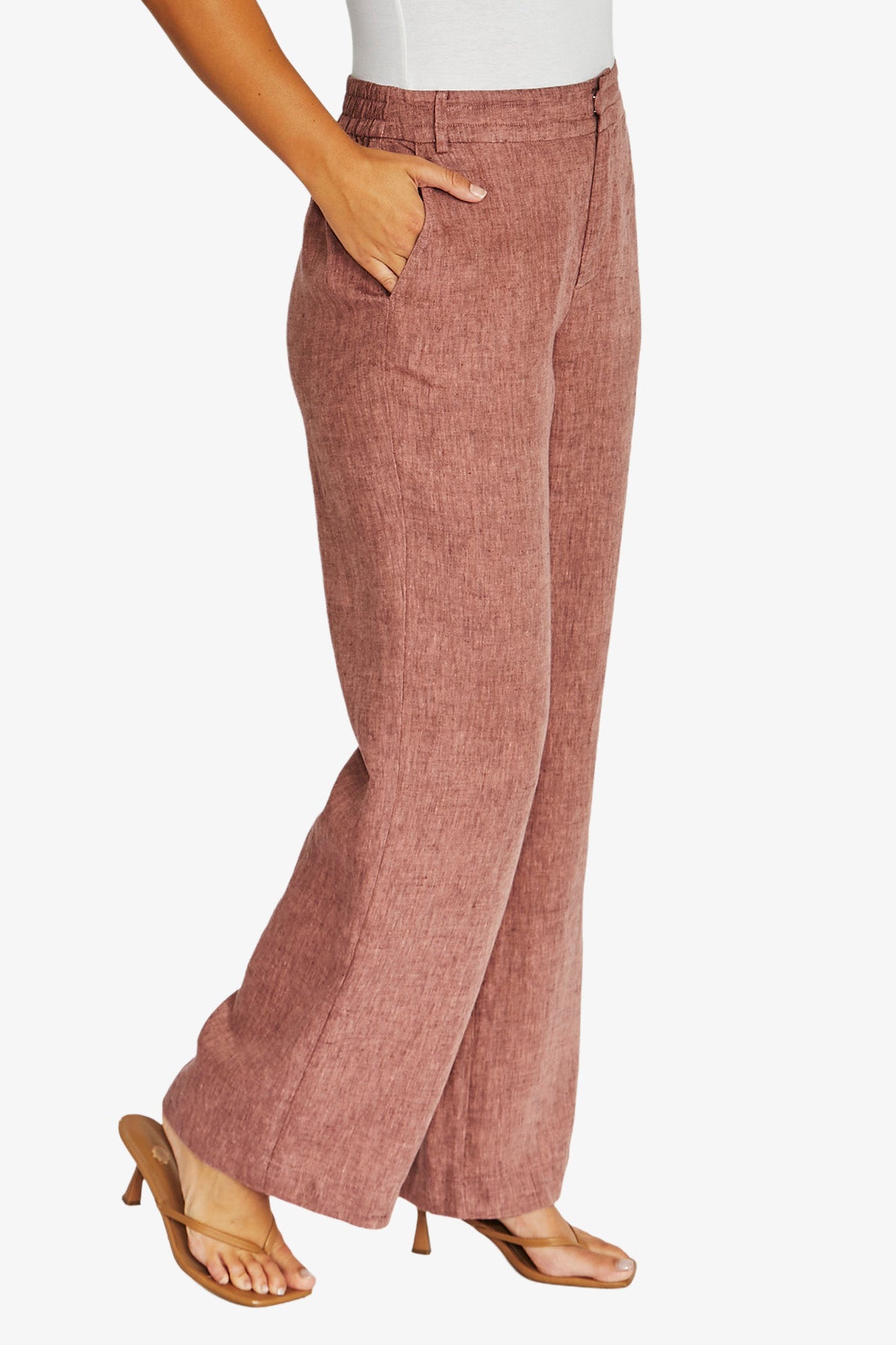 Side view dusty rose wide leg pants with a textured linen like fabric, paired with a white top and tan heeled sandals.