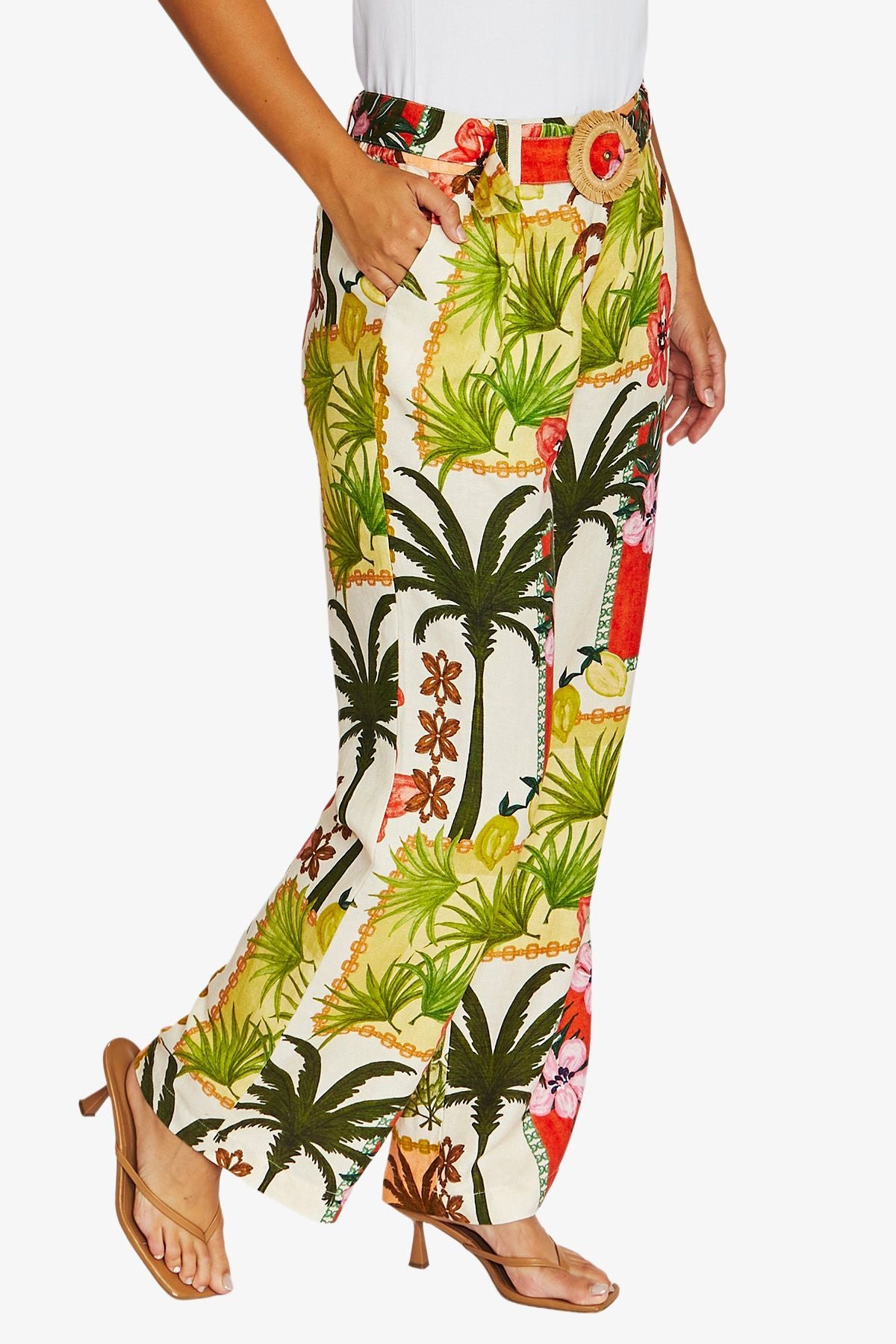 Side View high waisted, wide leg tropical print pants with a white top and tan heeled sandals, shown against a plain light gray studio background.