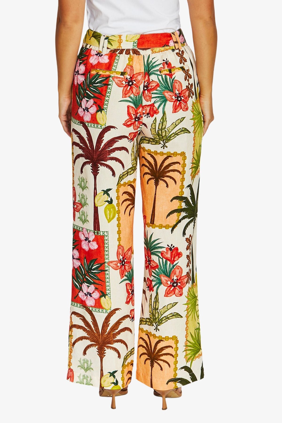 Back view of wide leg trousers featuring a vibrant tropical patchwork print with palm trees, hibiscus flowers, and beach motifs.