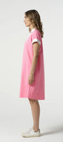 Woman wearing a pink dress with white trim on a white background