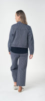Back view matching navy blue denim jacket and wide leg pants set, styled with a dark navy t-shirt and white slip on shoes.