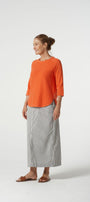 Woman wearing an orange top and gray pants on a white background