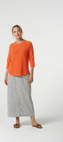 Woman wearing an orange top and gray skirt on a white background