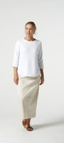 Woman wearing a white top and beige skirt on a white background
