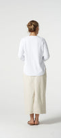 Person wearing a white long-sleeve shirt and beige pants on a white background