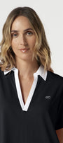 Woman wearing a black polo shirt with white collar and logo on a white background