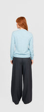 Person wearing a light blue sweater and dark gray wide leg pants.