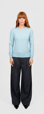 Woman wearing a light blue sweater and black pants.