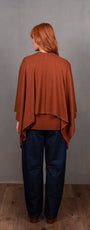 Person wearing a brown poncho and blue pants.