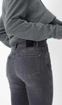 Person wearing a grey sweater and dark jeans 