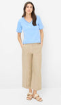 Front view  a light blue shirt and beige pants.