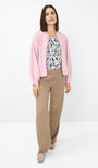 Woman wearing a pink jacket patterned top, and beige pants front view