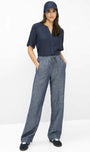 A woman modeling a navy blue short-sleeve button-up shirt and matching navy blue wide-leg drawstring pants, paired with a navy cap and black slip-on shoes, against a plain white studio background.
