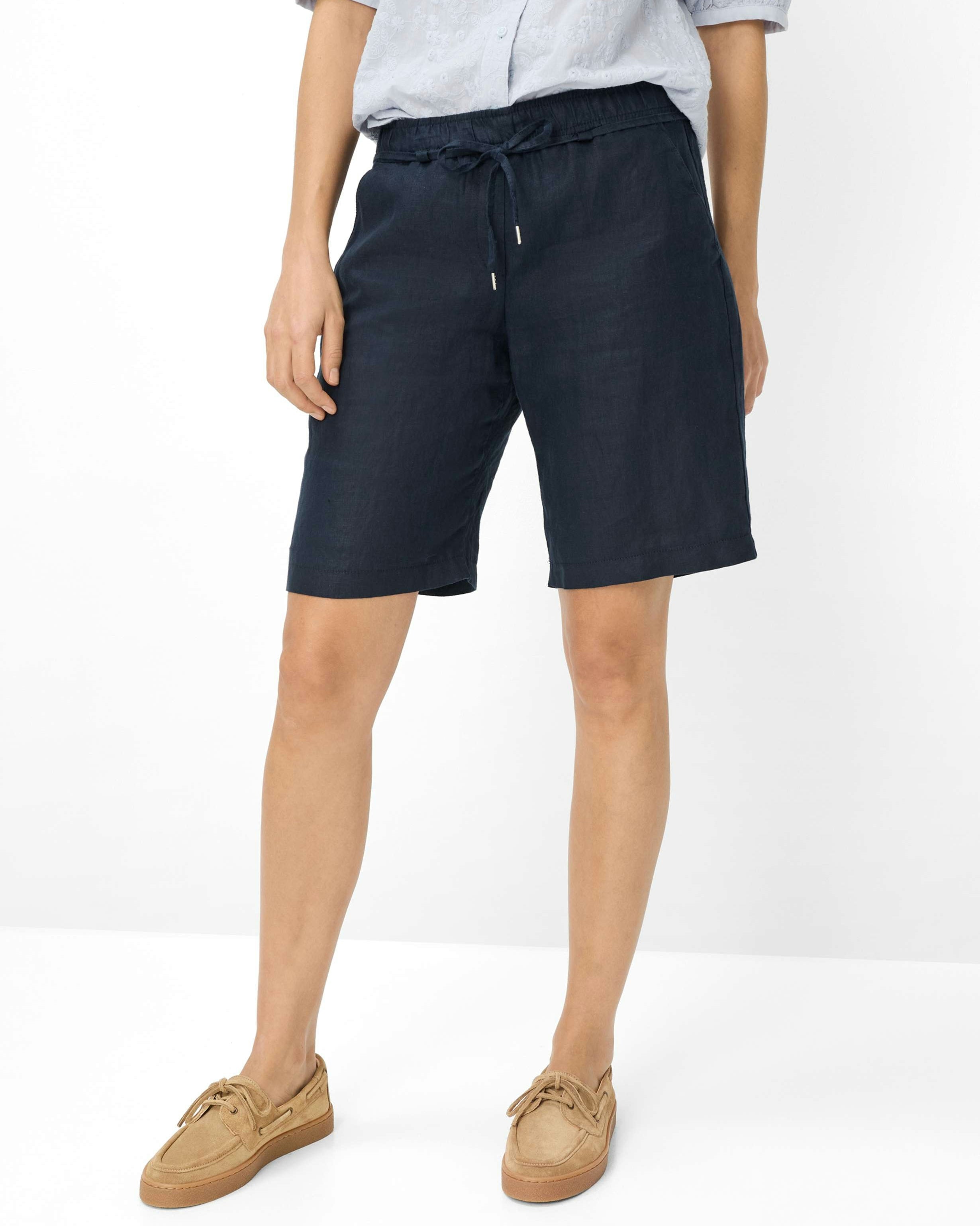  dark navy blue drawstring shorts, a light gray short sleeve shirt, and tan boat shoes, 