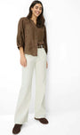A woman modeling a brown button-up blouse with lace sleeve details and light beige wide-leg trousers, standing against a plain white studio background.
